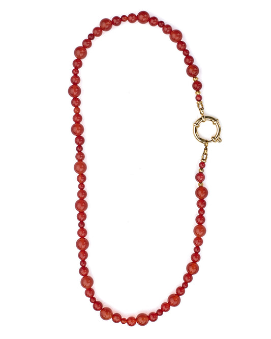 Red beaded necklace with a gold clasp on a white background
