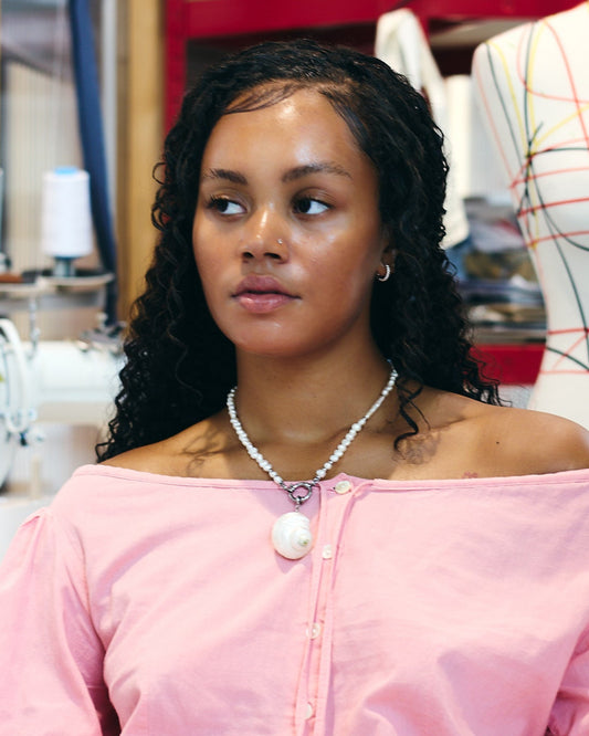 Woman wearing a pink off-shoulder top in a workshop setting