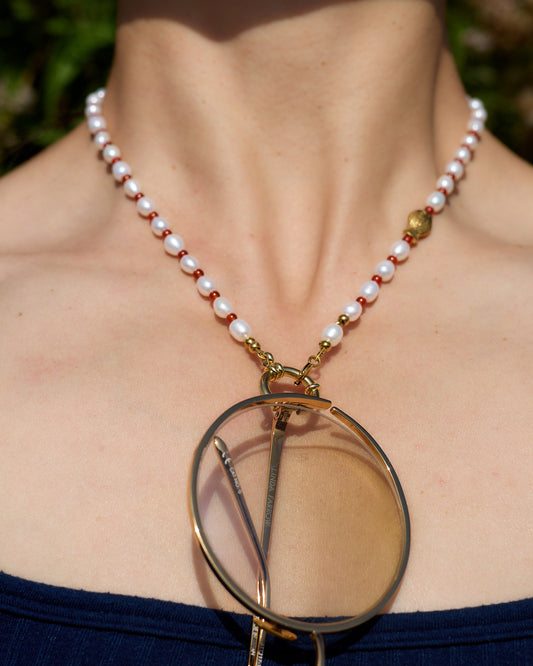 Pearl necklace with a circular pendant worn by a person