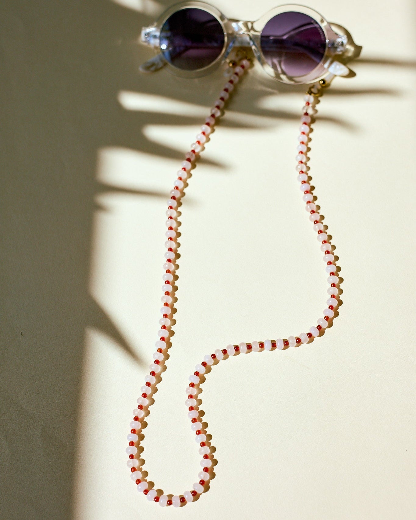 Sunglasses with a red and white beaded sunglasses chain on a light background
